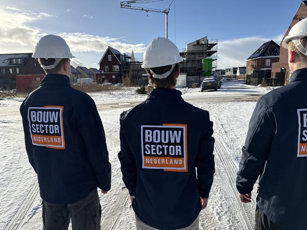 Drie medewerkers van Bouwsector Nederland met witte helm bij nieuwbouwwoningen in aanbouw